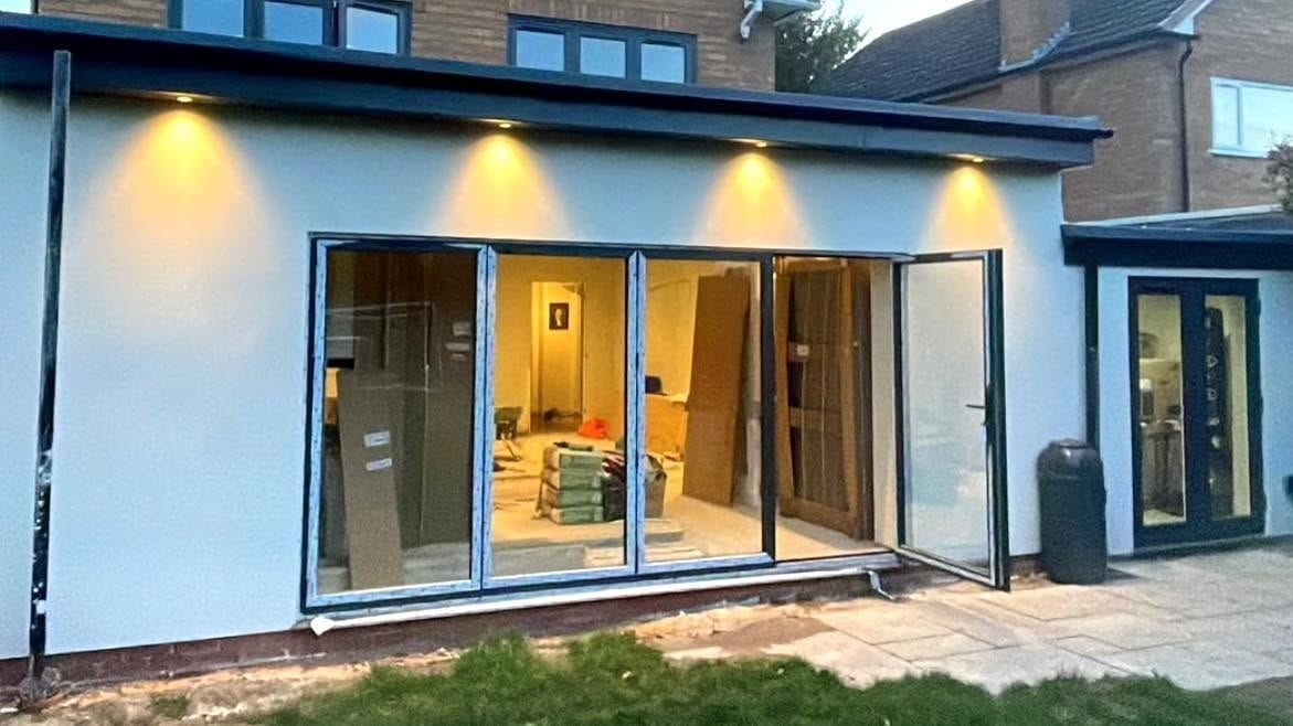 Rendered rear extension with bifold and French doors, lit at dusk, Bromsgrove