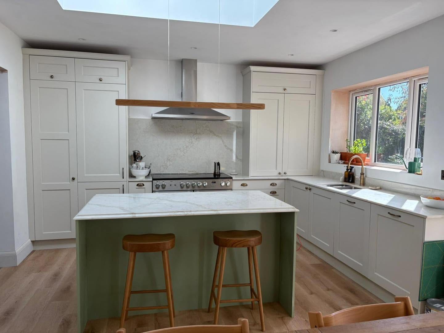 Open-plan kitchen in Bromsgrove with green island, range cooker and marble splashback