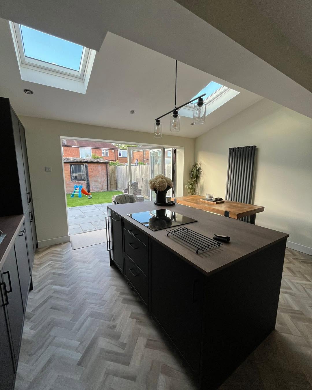 Finished open-plan kitchen extension with bi-fold doors, Velux skylights and dark shaker island