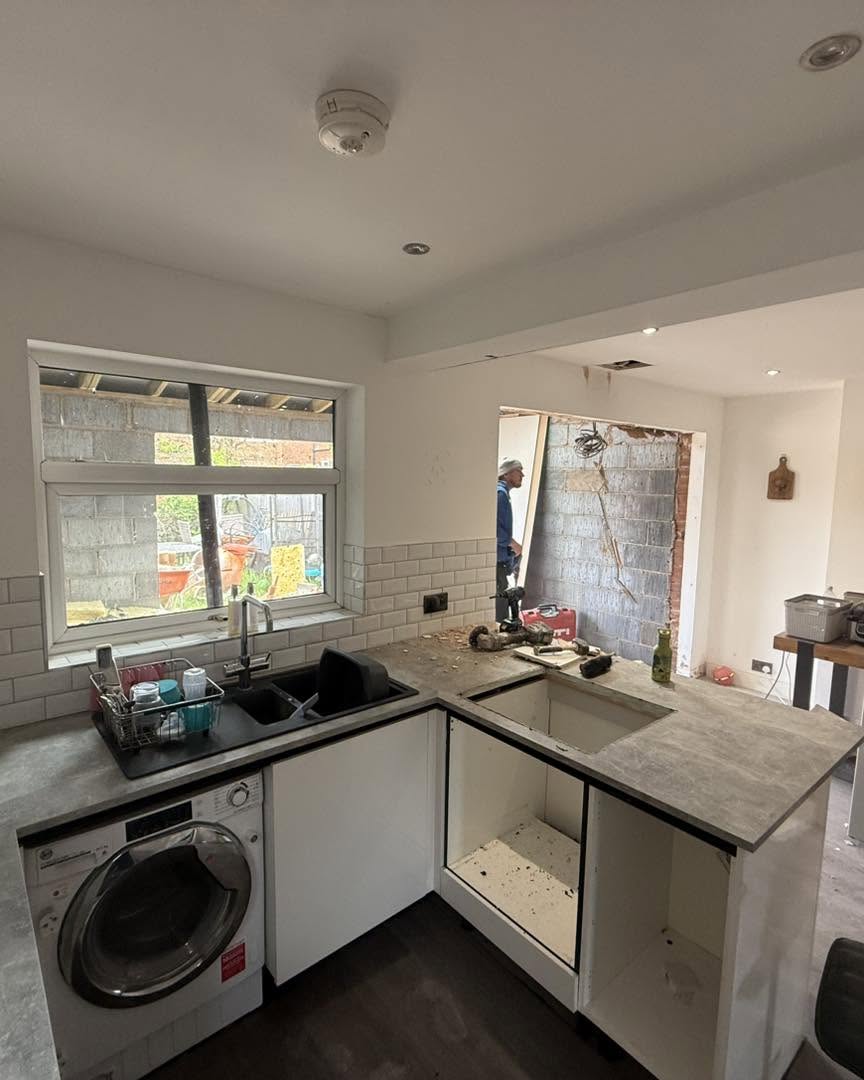 Existing kitchen mid-demolition with structural opening for new extension visible