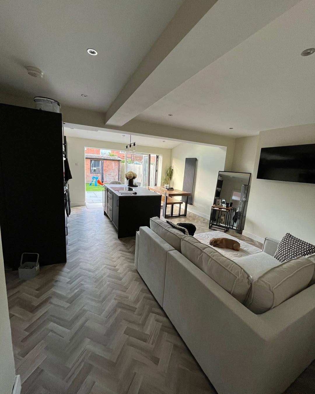 Open-plan kitchen-living-dining space with sofa, kitchen island and bi-folds in the distance