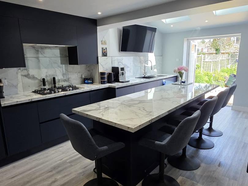 Modern finished kitchen extension with dark units, marble island and bi-folds onto garden